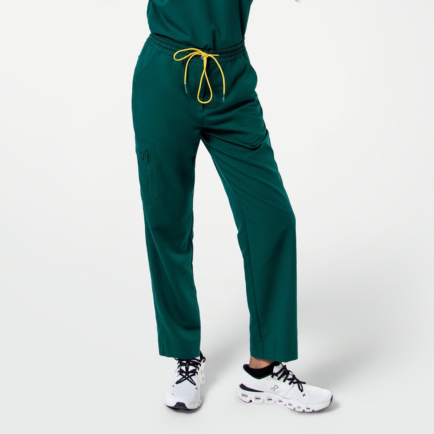 Image of Close-up of Pine Green zipper pocket split hem scrub pants with a yellow drawstring, shown from the waist down.